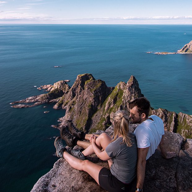 Bilde av 2 personer som sitter på en fjelltopp og nyter utsikten