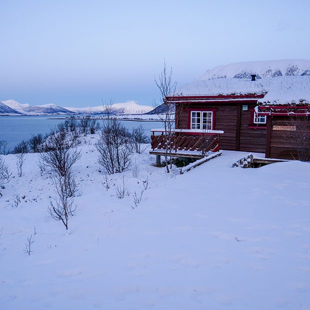 Bilde av ei hytte ved havet i vinterlandskap